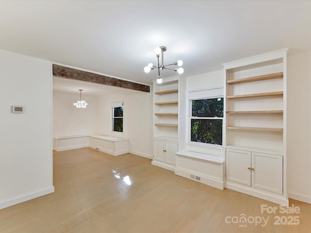 unfurnished living room with light hardwood / wood-style floors and a chandelier