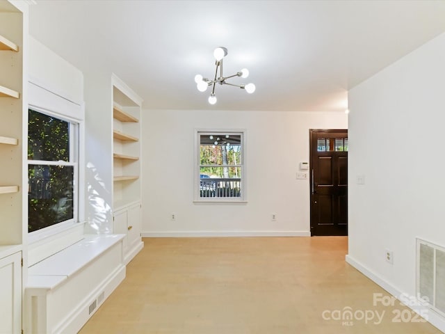 interior space with built in shelves, a chandelier, and light wood-type flooring