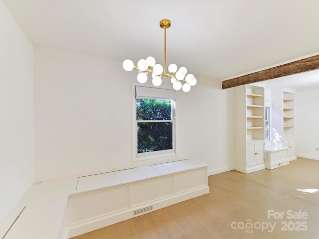 unfurnished dining area featuring wood-type flooring, built in features, and a chandelier