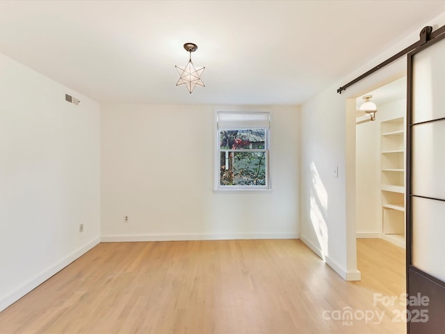 spare room featuring light hardwood / wood-style floors and a barn door