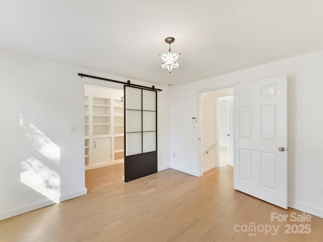 unfurnished room featuring wood-type flooring and a barn door