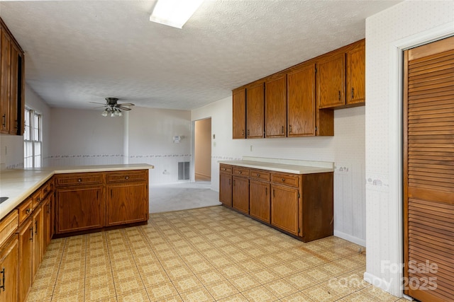 261 Lower Christ School Rd, Fletcher, NC 28732 - kitchen with a ceiling fan, light countertops, brown cabinets, a textured ceiling, and a peninsula
