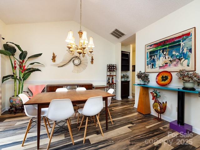 dining room featuring lofted ceiling, dark hardwood / wood-style floors, and an inviting chandelier