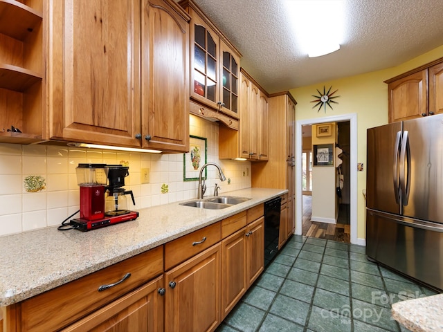 kitchen featuring stainless steel refrigerator, dishwasher, sink, and light stone counters