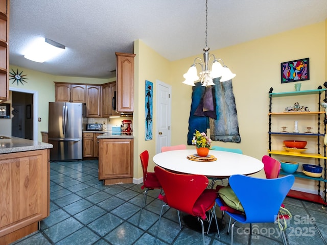 kitchen with stainless steel refrigerator, an inviting chandelier, hanging light fixtures, backsplash, and a textured ceiling