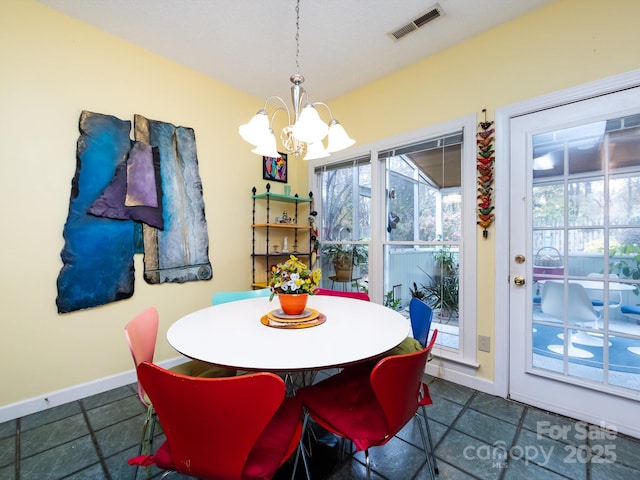 dining room featuring a notable chandelier, a healthy amount of sunlight, and dark tile patterned flooring