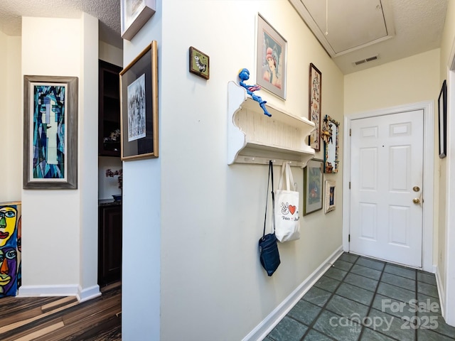 hallway with dark tile patterned floors and a textured ceiling