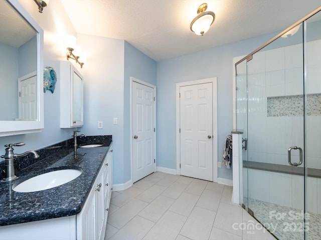 bathroom featuring a shower with door, vanity, tile patterned floors, and a textured ceiling