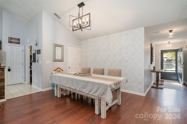 dining area with a chandelier, hardwood / wood-style flooring, and high vaulted ceiling