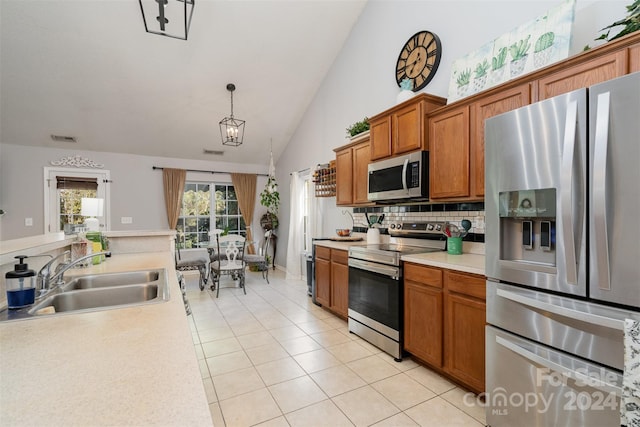 kitchen with sink, decorative backsplash, light tile patterned floors, decorative light fixtures, and stainless steel appliances