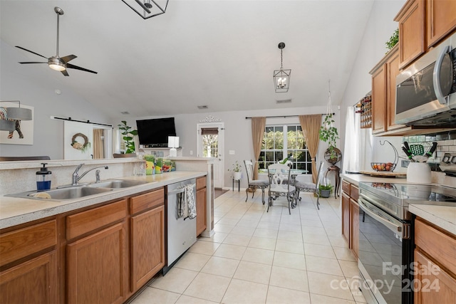 kitchen featuring sink, stainless steel appliances, a barn door, decorative light fixtures, and light tile patterned floors