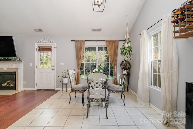 dining room featuring vaulted ceiling, a tiled fireplace, and light hardwood / wood-style flooring