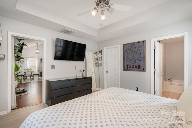 bedroom with ceiling fan, ensuite bath, and light hardwood / wood-style flooring