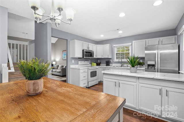 kitchen with pendant lighting, white cabinets, stainless steel appliances, and sink