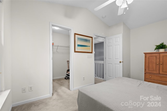 bedroom featuring ceiling fan, light colored carpet, lofted ceiling, a walk in closet, and a closet