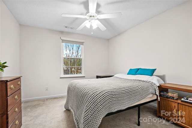 bedroom with ceiling fan, light colored carpet, and a textured ceiling