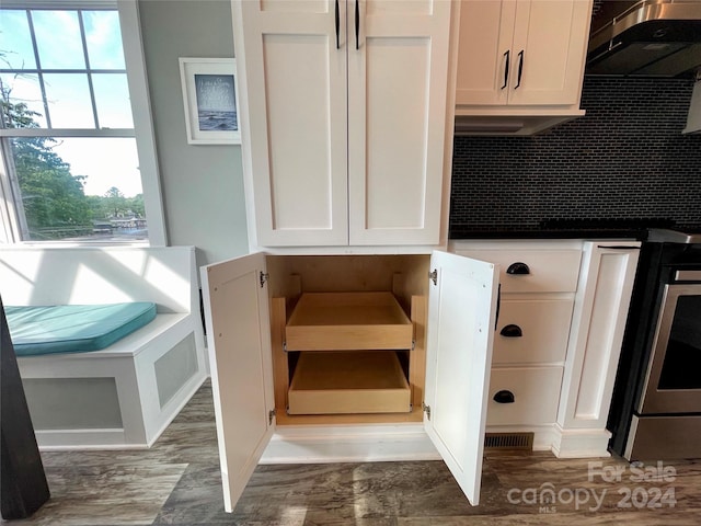 interior space with backsplash, white cabinetry, stainless steel range oven, and ventilation hood