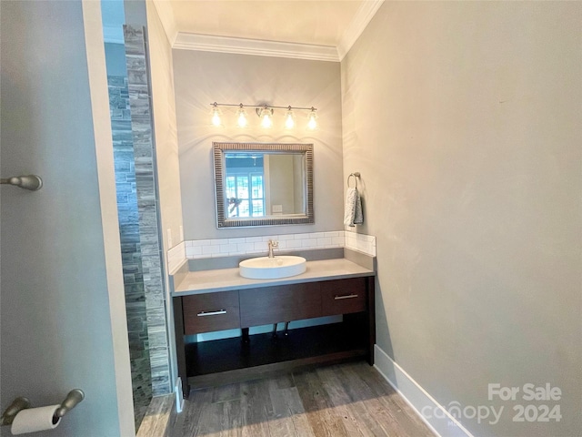 bathroom with wood-type flooring, vanity, tasteful backsplash, and crown molding