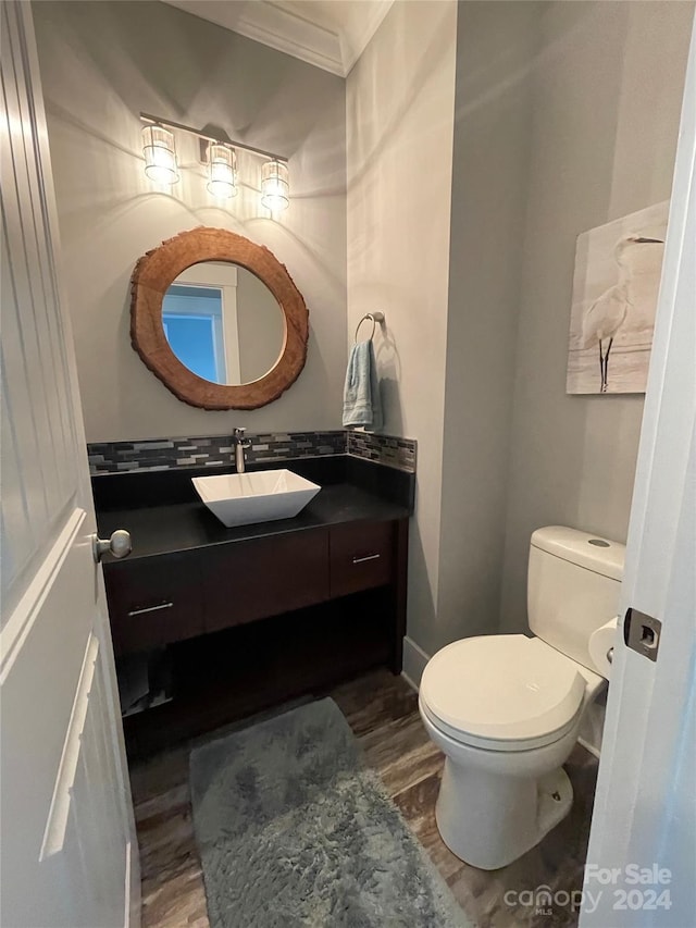 bathroom with toilet, vanity, ornamental molding, and hardwood / wood-style flooring