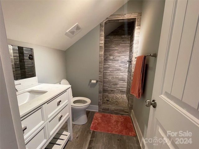 bathroom with vanity, lofted ceiling, hardwood / wood-style flooring, toilet, and walk in shower