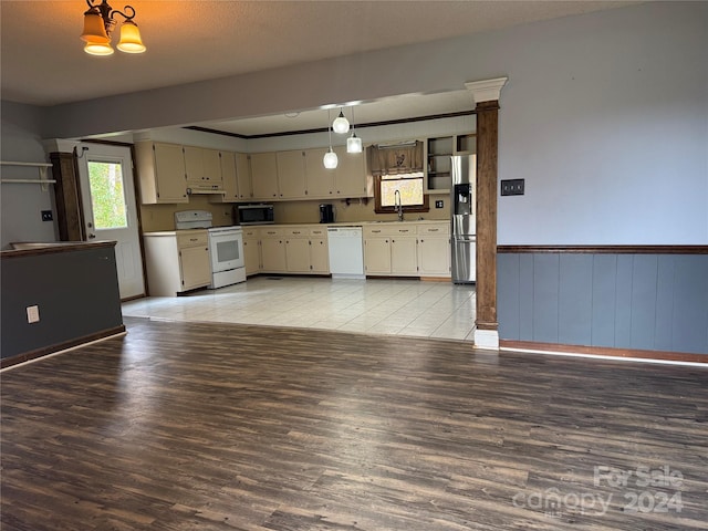 kitchen with appliances with stainless steel finishes, light wood-type flooring, sink, pendant lighting, and a chandelier