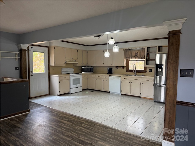 kitchen featuring appliances with stainless steel finishes, light wood-type flooring, ornamental molding, cream cabinets, and hanging light fixtures