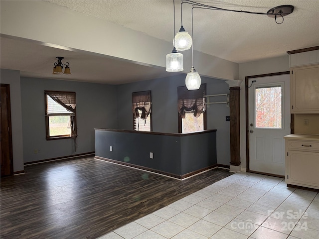 interior space with pendant lighting, a textured ceiling, an inviting chandelier, and light hardwood / wood-style flooring