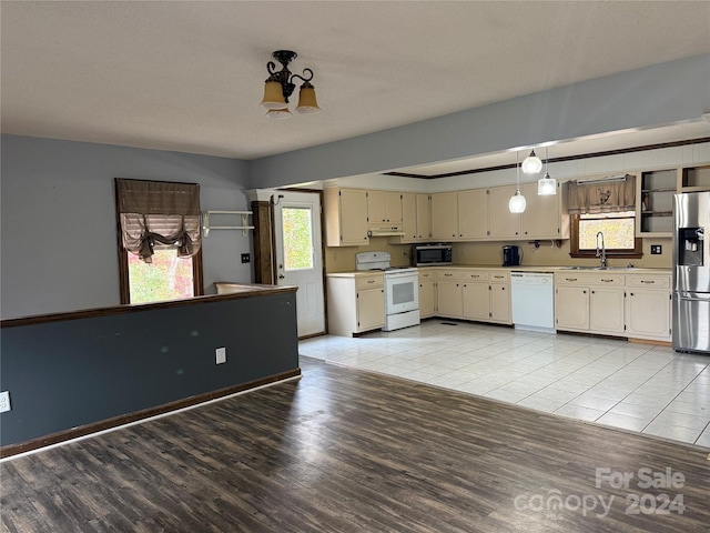 kitchen with sink, stainless steel appliances, decorative light fixtures, cream cabinetry, and light wood-type flooring