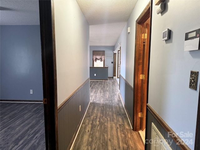 corridor with dark hardwood / wood-style floors and a textured ceiling