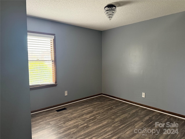 empty room with a textured ceiling and dark hardwood / wood-style floors