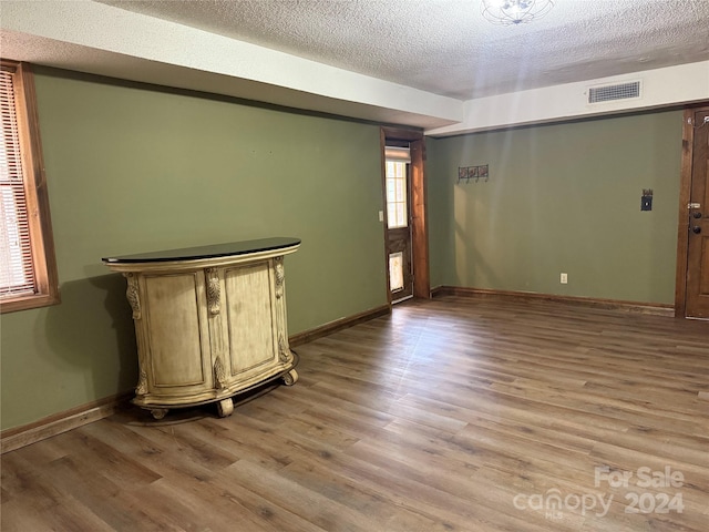 empty room with hardwood / wood-style floors and a textured ceiling