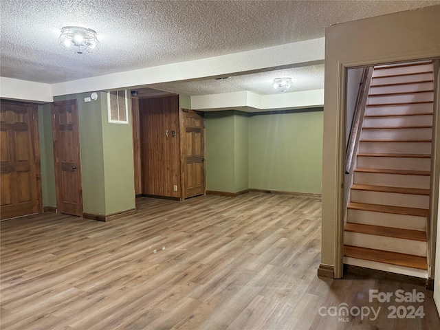 basement featuring light hardwood / wood-style flooring and a textured ceiling