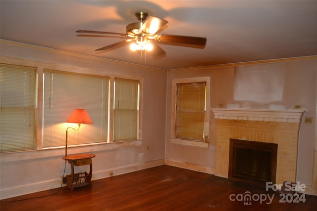 unfurnished living room featuring dark hardwood / wood-style floors, a brick fireplace, ceiling fan, and ornamental molding