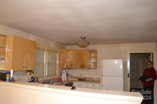 kitchen with kitchen peninsula, white refrigerator, and sink