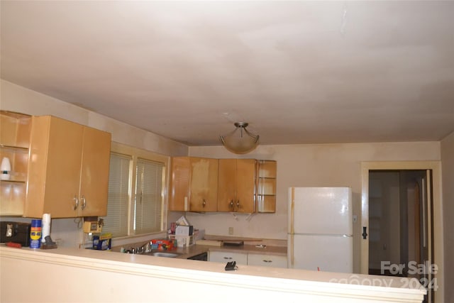 kitchen featuring kitchen peninsula, sink, and white fridge