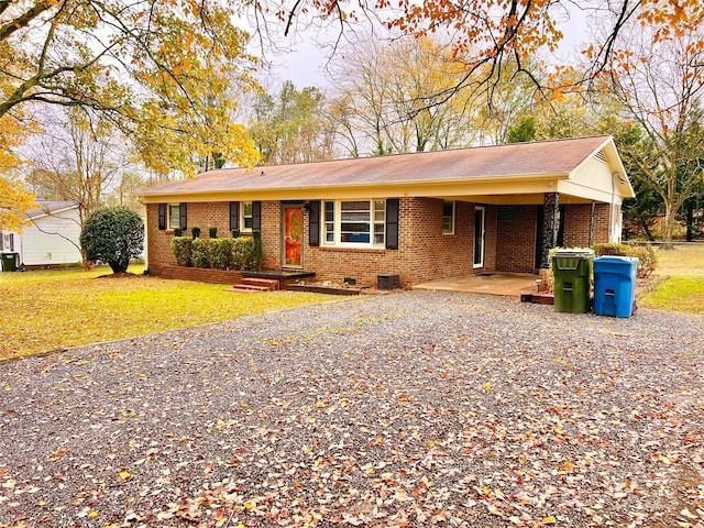 ranch-style house featuring driveway, brick siding, a front lawn, and crawl space