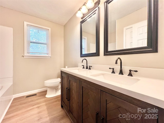 bathroom featuring toilet, visible vents, a sink, and wood finished floors