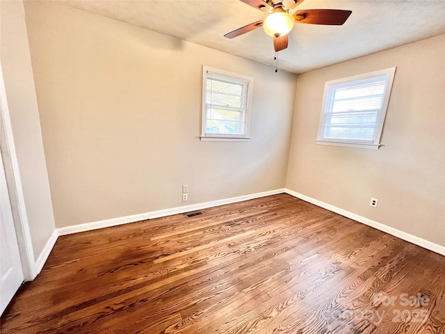 spare room with a wealth of natural light, baseboards, visible vents, and wood finished floors