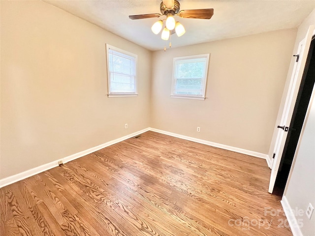 spare room featuring baseboards, ceiling fan, visible vents, and light wood-style floors