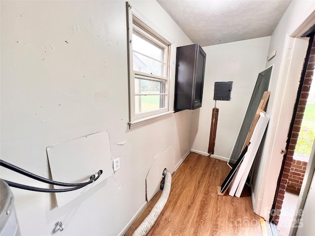 laundry area with light wood-type flooring, laundry area, baseboards, and a textured ceiling