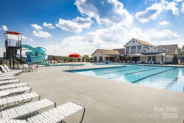 view of swimming pool with a water slide and a patio