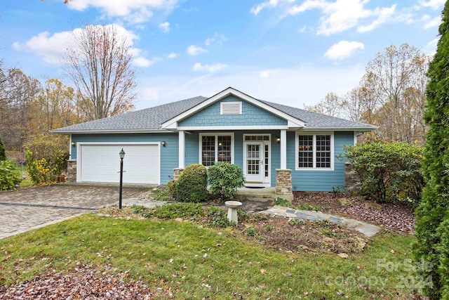 view of front of home featuring covered porch, a garage, and a front yard