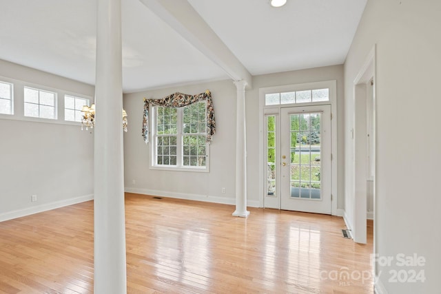 interior space with an inviting chandelier, light wood-type flooring, and decorative columns