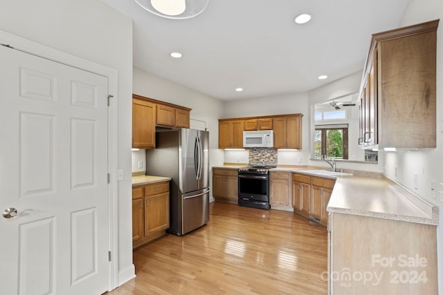 kitchen featuring decorative backsplash, appliances with stainless steel finishes, light hardwood / wood-style flooring, and sink