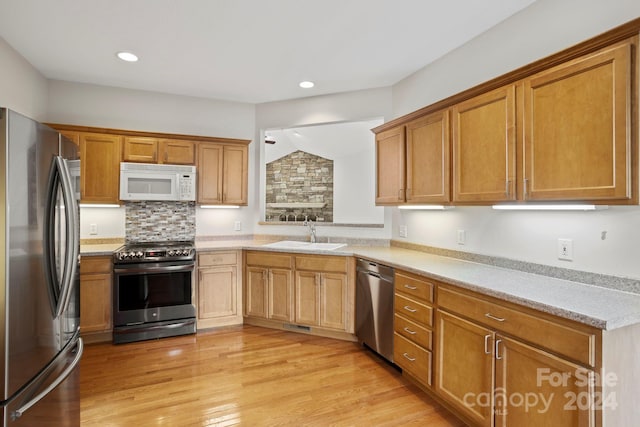 kitchen featuring vaulted ceiling, sink, stainless steel appliances, and light hardwood / wood-style flooring