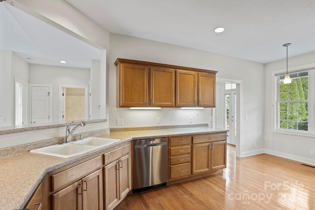 kitchen with decorative light fixtures, light hardwood / wood-style floors, stainless steel dishwasher, and sink