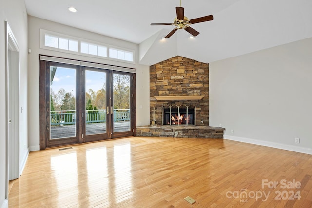 unfurnished living room with light hardwood / wood-style floors, a fireplace, high vaulted ceiling, and french doors