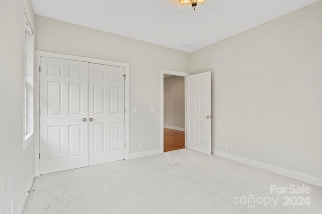 unfurnished bedroom with a closet and light colored carpet