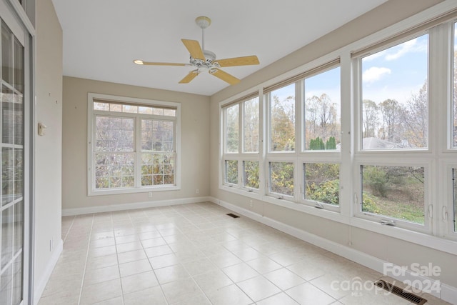 unfurnished sunroom featuring ceiling fan and a wealth of natural light