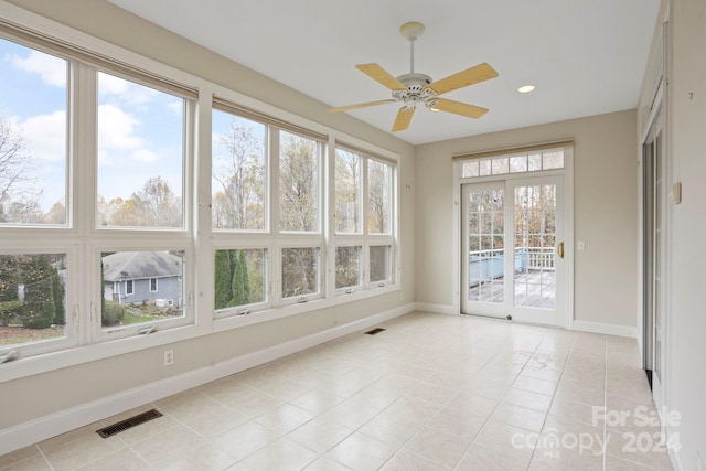 unfurnished sunroom featuring ceiling fan and a healthy amount of sunlight